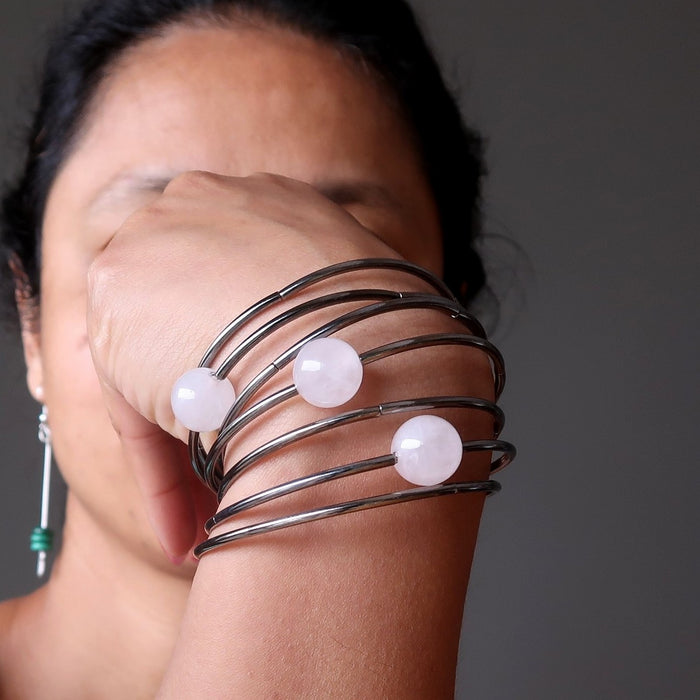 7 layer gunmetal bracelet with three statement beads in pink rose quartz being modeled on a woman