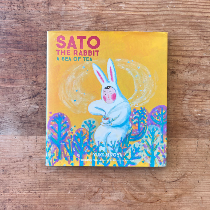 Book titled 'Sato the Rabbit: A Sea of Tea' on a wooden surface