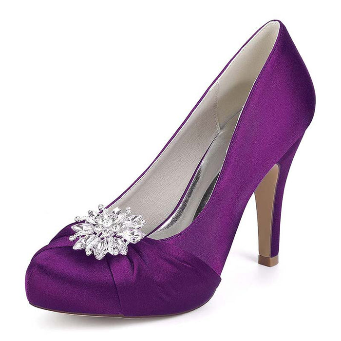 Purple high-heeled shoe with a decorative brooch on a white background