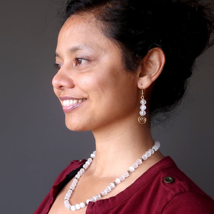 sheila of satin crystals wearing white selenite gold spiral dangle earrings and selenite necklace
