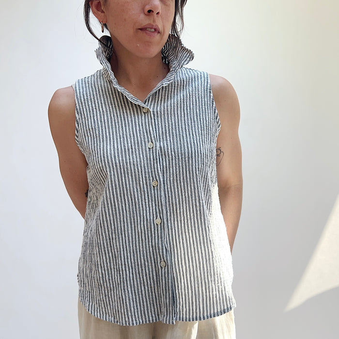 Person wearing a sleeveless striped shirt against a plain background
