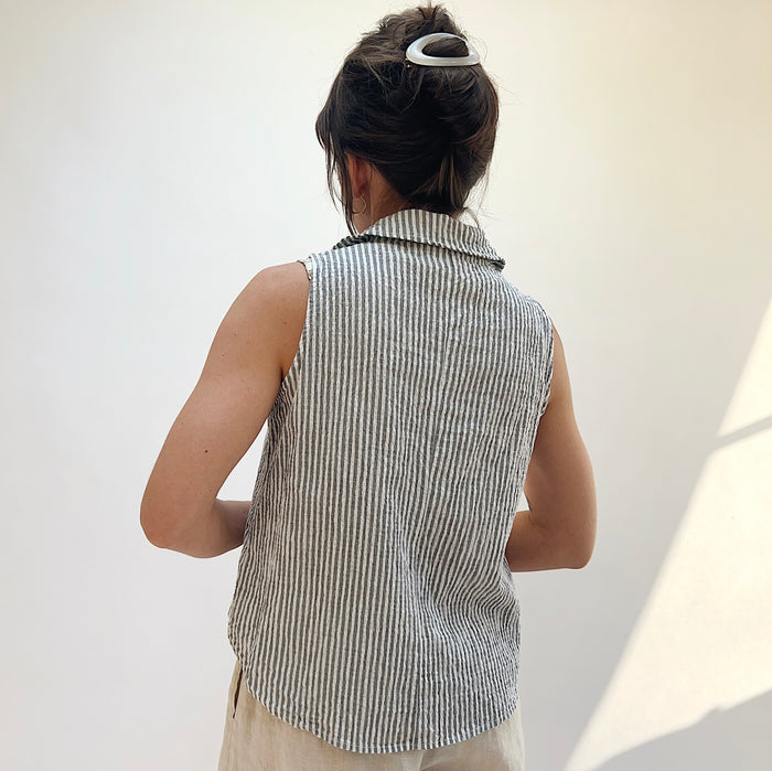 Person wearing a sleeveless striped shirt against a plain background