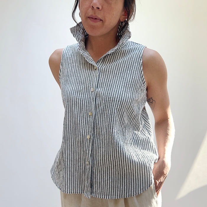 Person wearing a sleeveless striped shirt against a plain background