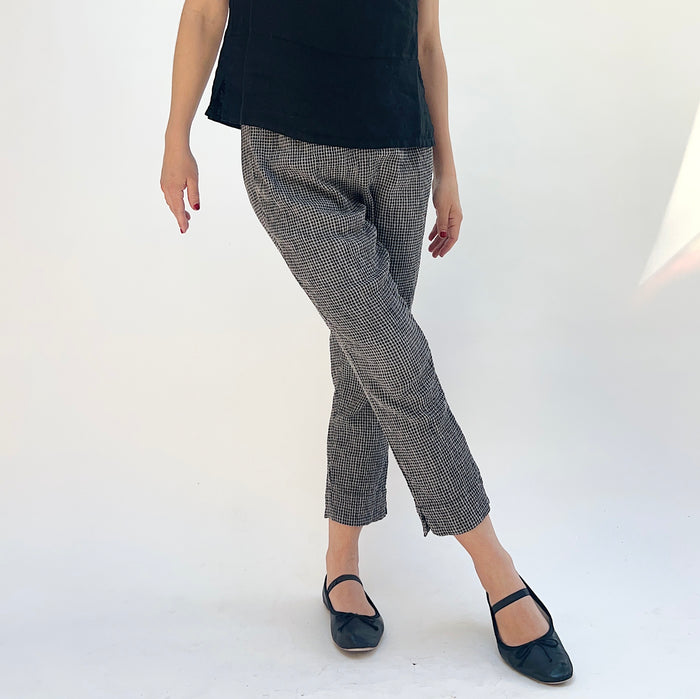Person wearing black and gray checkered pants on a white background