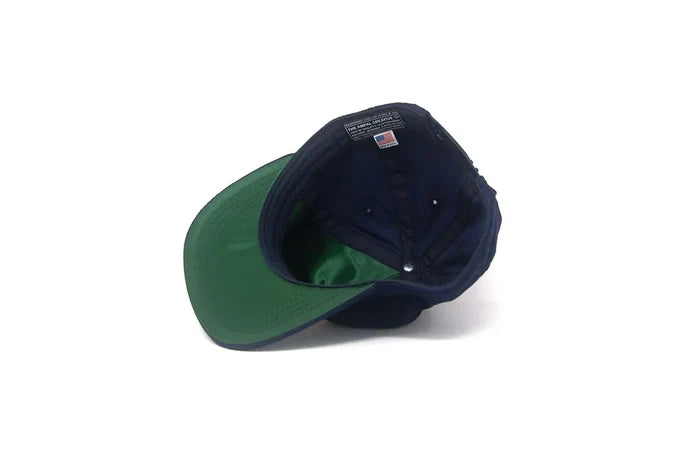 Interior view of the Tiger III Navy Snapback in Corduroy showing the green satin underbrim and The Ampal Creative label