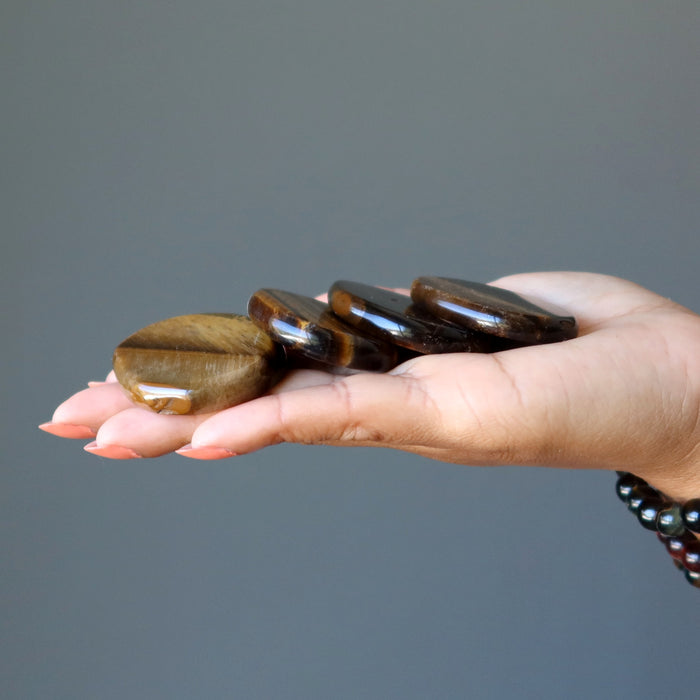holding 4 tigers eye slabs on the palm