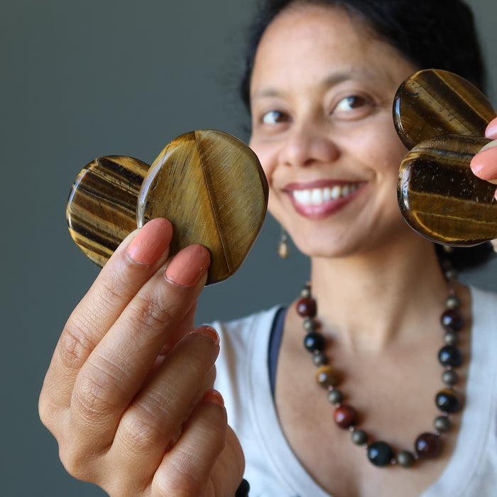 sheila of satin crystals holding two Tigers Eye Polished Slabs on each hand