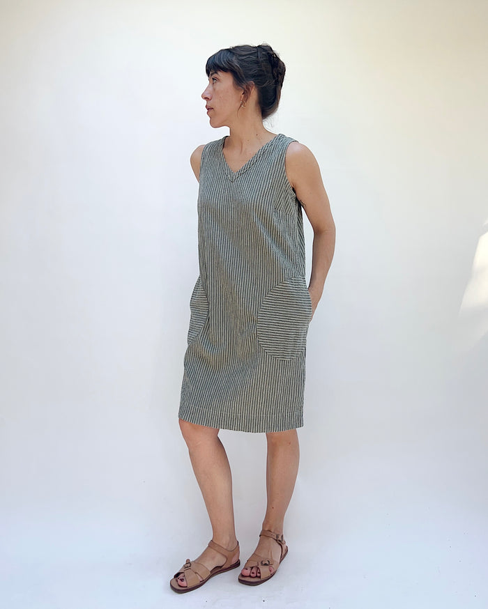 Woman wearing a sleeveless dress with stripes against a white background