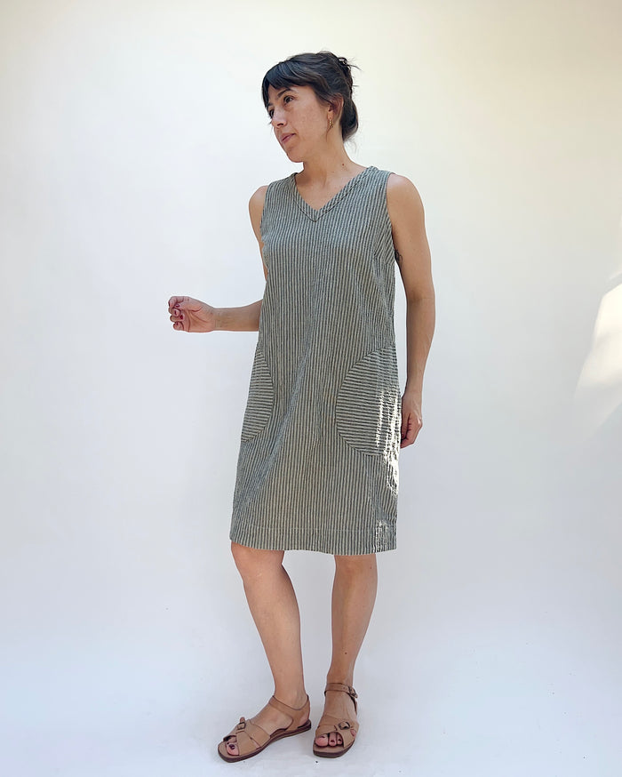 Woman wearing a sleeveless, patterned dress against a white background